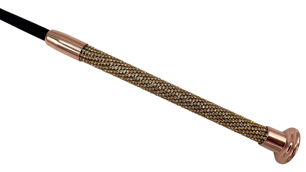 Nahaufnahme des kunstvoll verzierten Griffs einer Gerte, besetzt mit rosegoldenen Glitzersteinen und abschließendem Metallknauf in Roségold