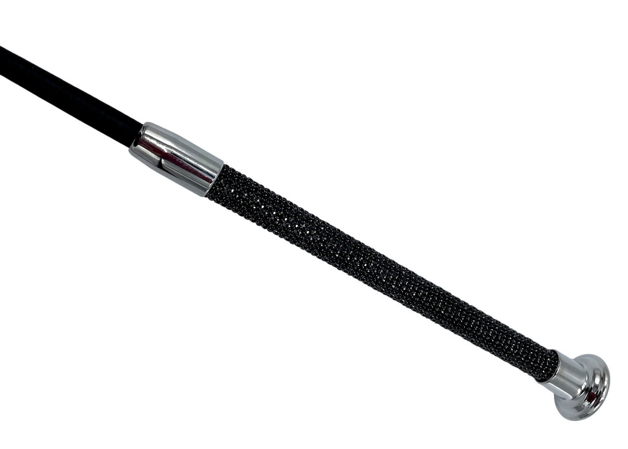 Detailaufnahme des edlen Griffs einer Gerte, besetzt mit schwarzen Glitzersteinen und abgeschlossen durch einen massiven silberfarbenen Metallknauf.