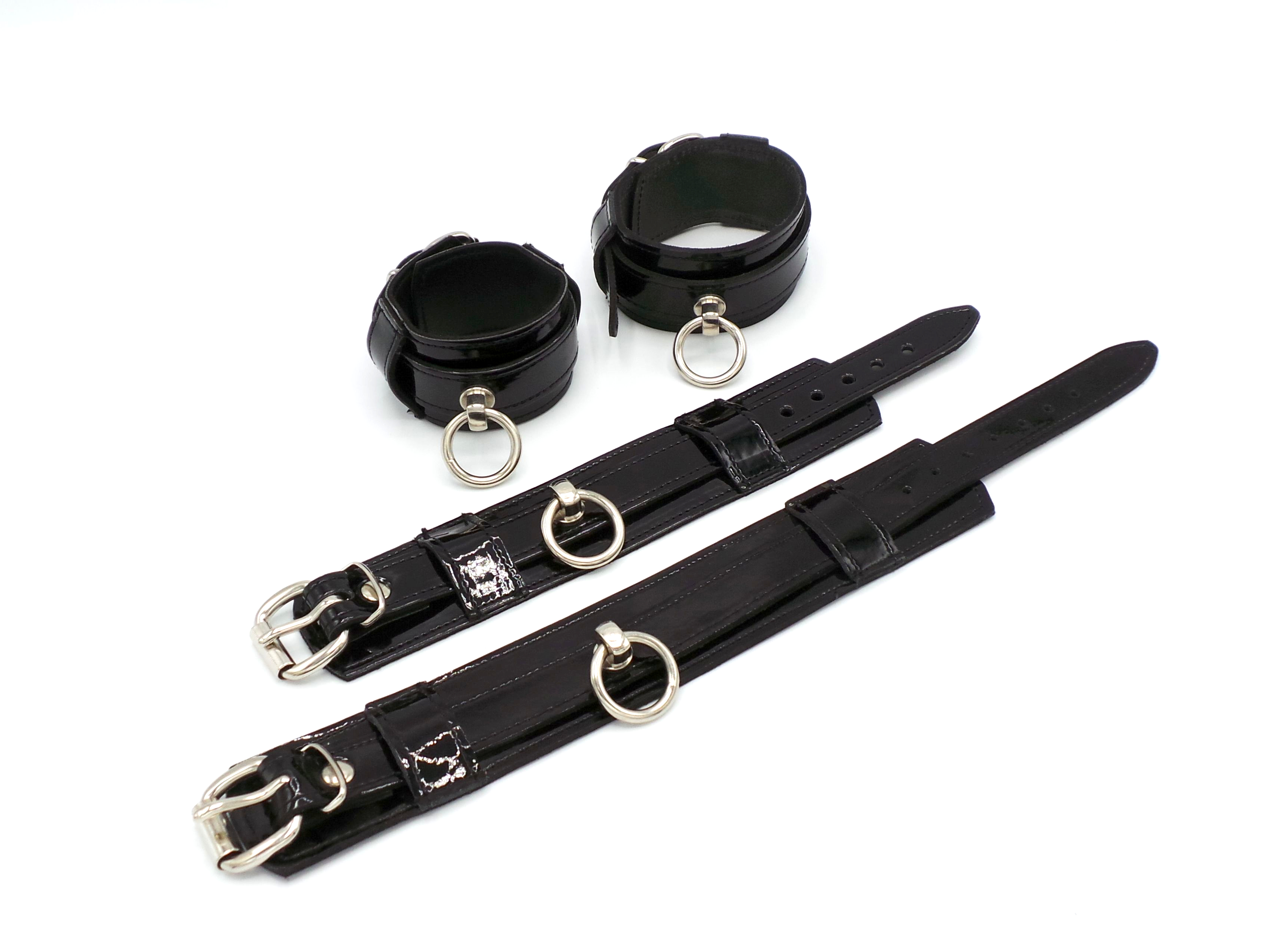 Set aus Hand- und Fußfesseln aus Lackleder mit glänzender Oberfläche und Ring der O – komfortabel innen mit Rindsleder