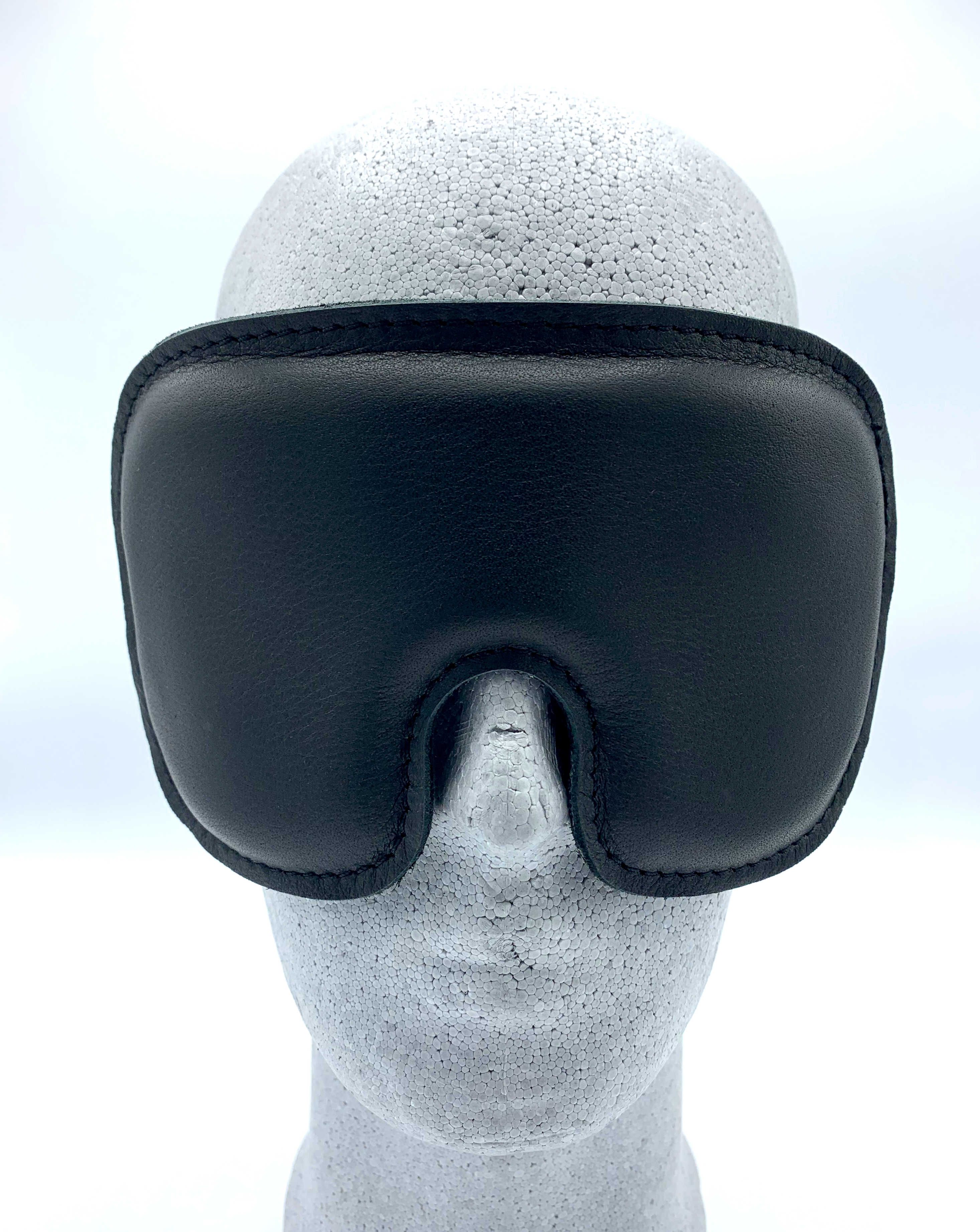 Schwarze Augenmaske aus Rindsleder mit weicher Schaumstoffpolsterung und zwei elastischen Bändern, sorgt für perfekten Sitz und absolute Dunkelheit.