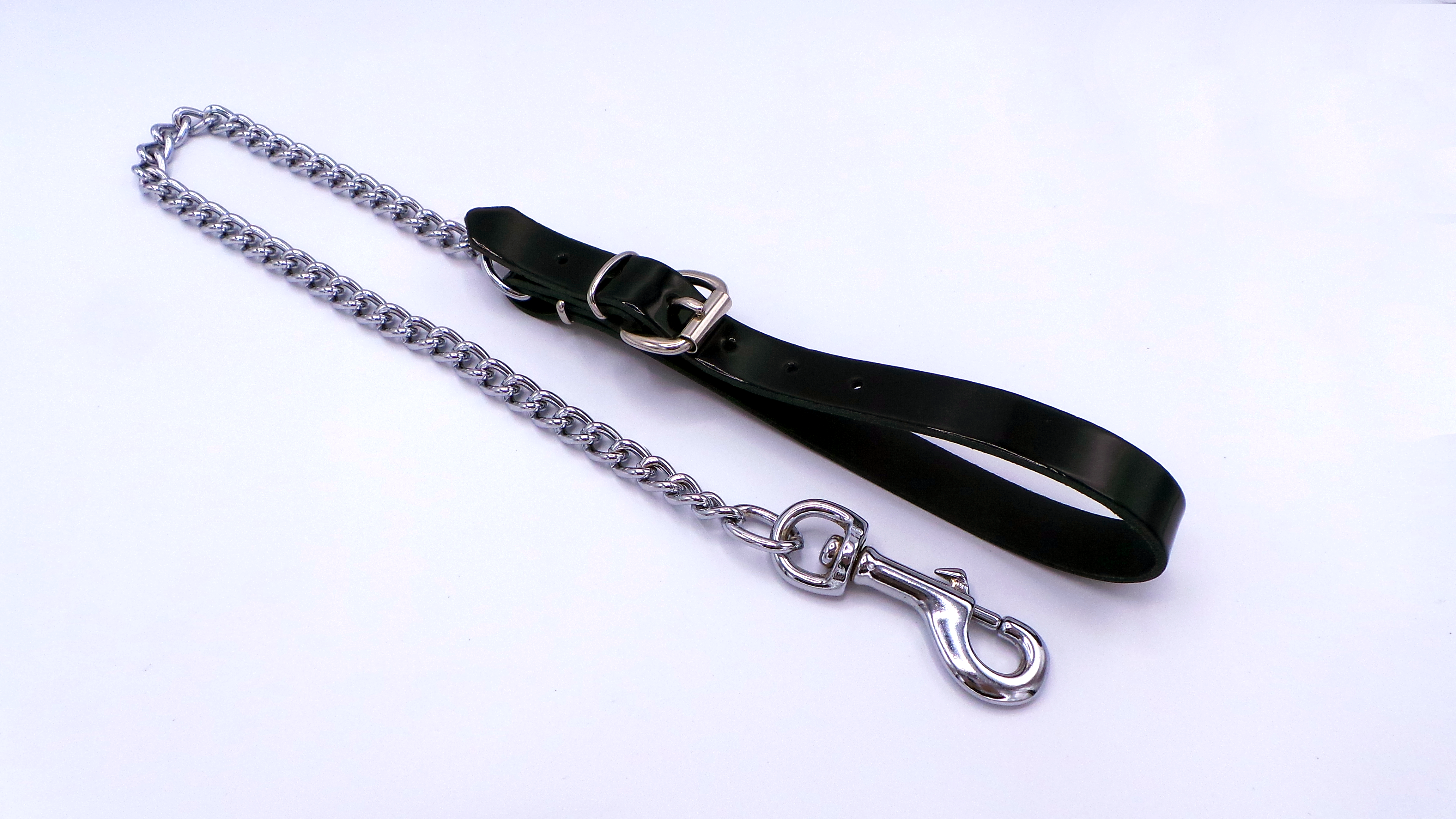 Nahaufnahme der glänzenden schwarzen Lacklederschlaufe mit Metallschnalle und Ösen, innen aus stabilem Rindsleder gefertigt.